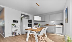 Functional kitchen with central island, appliances, and pendant light.