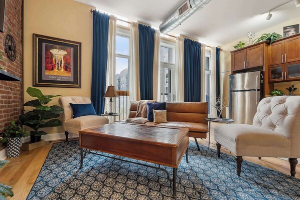 A cozy living room with a sofa, armchairs, a coffee table, and a patterned rug.