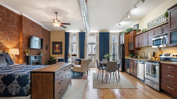 Una cocina moderna con electrodomésticos de acero inoxidable, un comedor con mesa y sillas, y un dormitorio con una cama grande y cómoda.