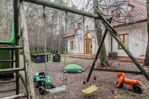 A rustic outdoor play area with swings, a small tractor, and a toy horse. - Lumina Amazing House w/ Terrace in Warsaw I 12 guests (Warszawa BIG)