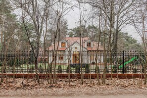 Una casa con techo de tejas, rodeada de una cerca y árboles.