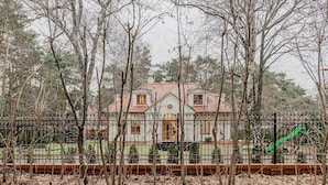 A house with a tiled roof, surrounded by a fence and trees. - Lumina amazing house in Warsaw (Warszawa BIG)