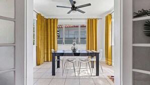 A dining area with a table and chairs, a ceiling fan, and yellow curtains. - Retro Rewind, Stylish, Near Design District Miami (Miami)
