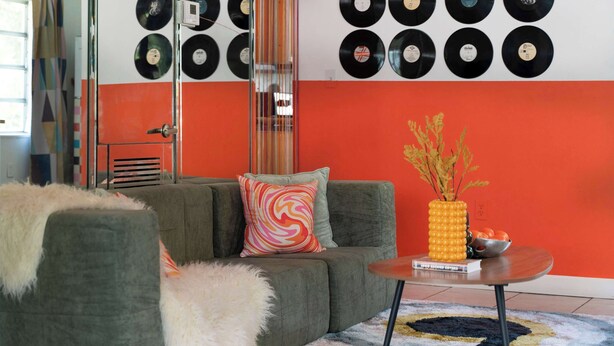 A living room with a sofa, a coffee table, a wall decorated with vinyl records, and a vase with branches. - Retro Rewind, Stylish, Near Design District Miami (Miami)