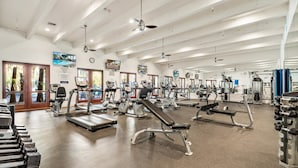 Une salle de sport spacieuse équipée de divers appareils d’exercice, notamment des tapis de course, des vélos d’appartement et des appareils de musculation.