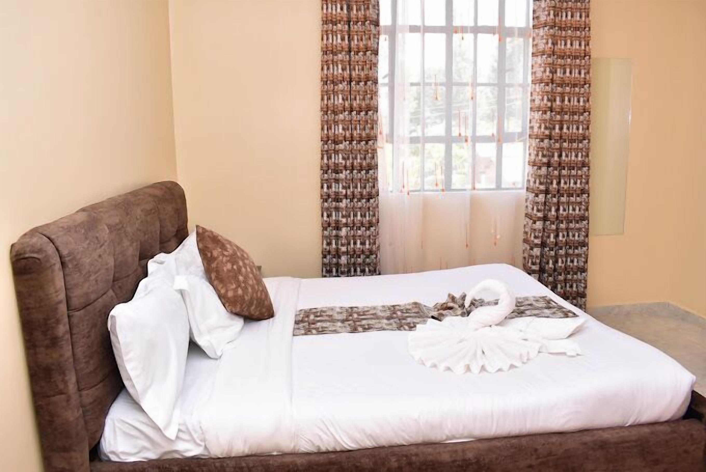 A neatly made bed with white linens and a decorative swan pillow.