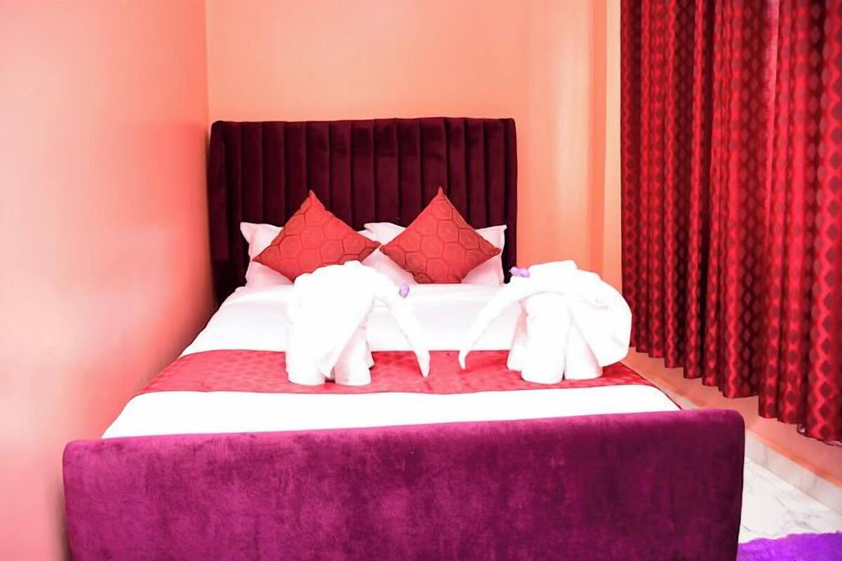 A neatly made bed with a red headboard, white bedding, and red and white pillows.