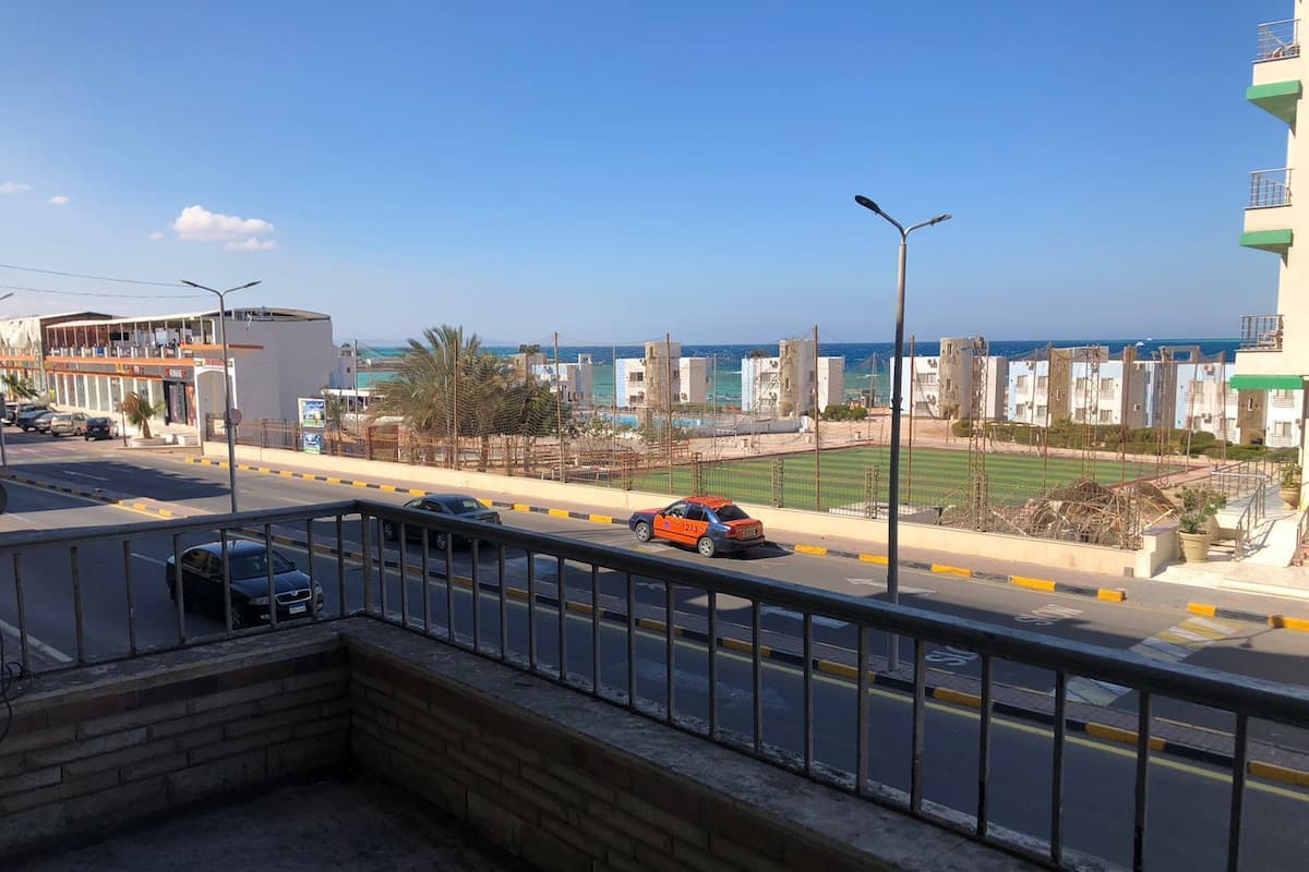 A coastal road with vehicles, a clear sky, and buildings in the background.