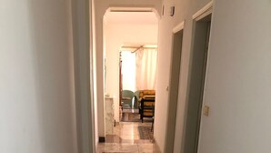 A hallway with a patterned carpet, white walls, and a tiled floor.
