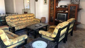 A living room with a sofa set, a coffee table, a television, and a cabinet with decorative items.