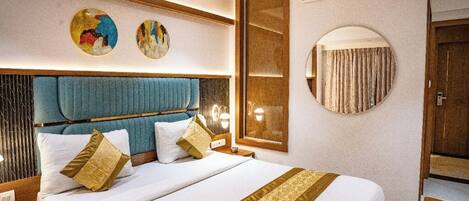 A hotel room with a large bed, a headboard, bedside tables, a mirror, and artwork on the wall.