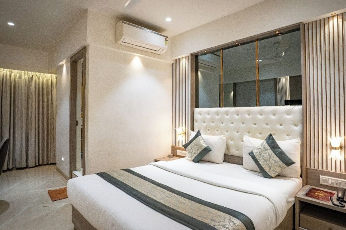 Moderni hotellihuone, jossa on suuri sänky, yöpöytä ja peili.