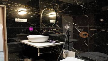 Ein modernes Badezimmer mit einem schwarzen Marmorwaschbecken, einem runden Spiegel und einer weißen Toilette.