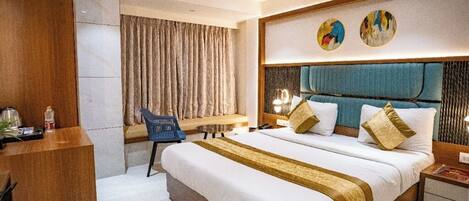 A modern hotel room with a large bed, a desk, and a chair.