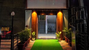 A hotel named Spencer with a neon sign, a green carpet, and potted plants. - Hotel Spencer- Kharghar Navi Mumbai (Panvel)