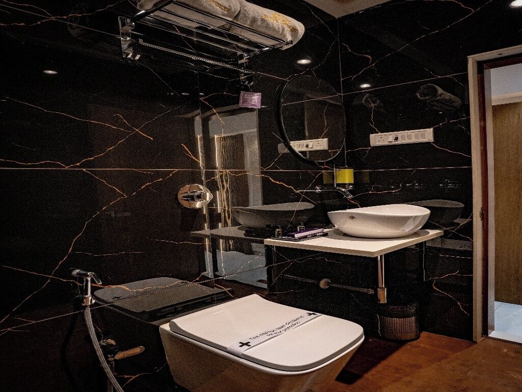 Un baño moderno con pared de mármol negro, lavamanos blanco y un inodoro.
