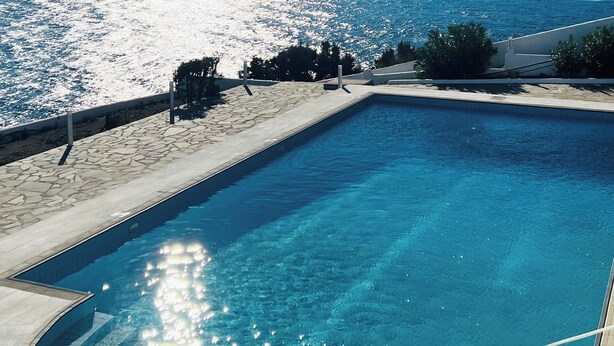 Una piscina con vistas al mar y colinas.