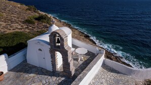 Un edificio blanco con una escalera de piedra y una pequeña mesa con sombrilla, con vistas al mar.