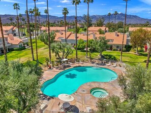 A residential area with a swimming pool, surrounded by palm trees and houses with red-tiled roofs. - Golf Resort Escape | Fairway Views + Pools & Pickleball (Palm Desert)
