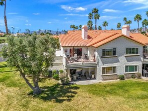 A two-story house with a red-tiled roof, a balcony, and a patio area.