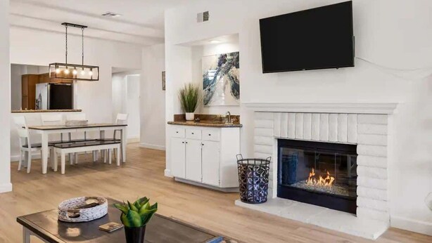 Una sala de estar moderna con chimenea, un comedor y una cocina.