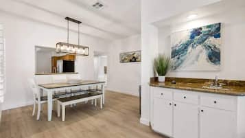 Una cocina moderna con armarios blancos, encimera de granito y un cuadro abstracto grande sobre el fregadero.
