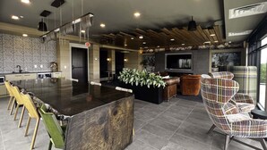 Une cuisine moderne dotée d’un grand îlot central, de tabourets de bar et d’un coin salon avec un fauteuil à motifs.