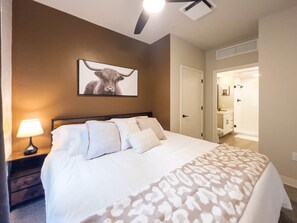 A bedroom with a bed, a nightstand with a lamp, a ceiling fan, and a framed picture on the wall. - Botanicals & Cattle Vibes | Two-Suite Vista Escape (Boise)