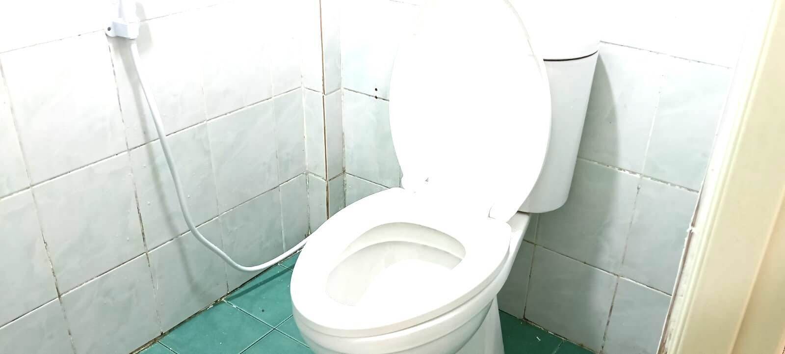 A white toilet with a closed lid in a small, tiled bathroom.