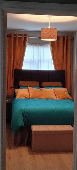 A bedroom with a bed, curtains, a bench, and a hanging light fixture. - Bangor - 2 Bed Apartment- Sleeps 4 -privateparking (Bangor)