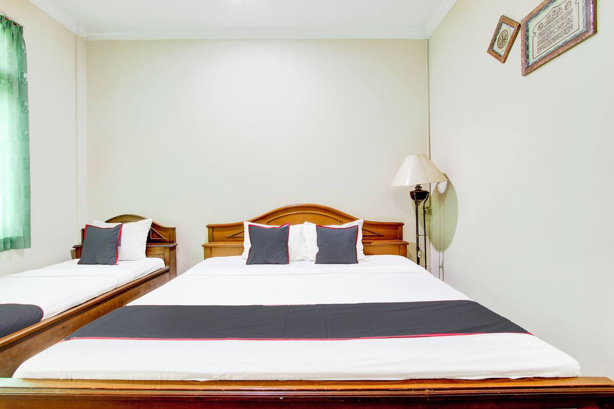 A double bed with a wooden headboard, two bedside tables, and a nightstand with a lamp.