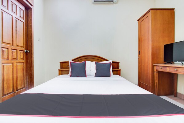 A bedroom with a bed, wooden wardrobe, and a desk with a television. - Hotel O Manahan Near Stadium Manahan Solo Formerly Atma Bhakti (Surakarta)