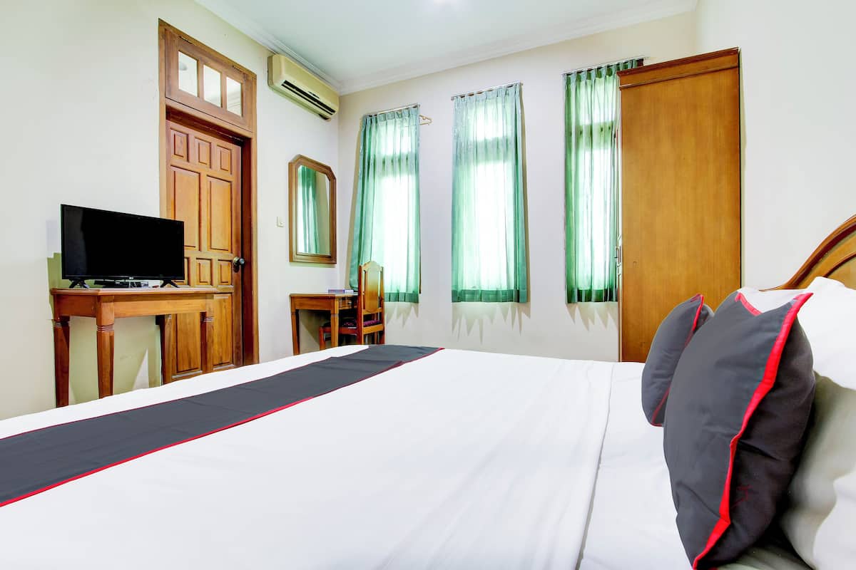 A hotel room with a bed, a desk with a television, a chair, and a wardrobe.