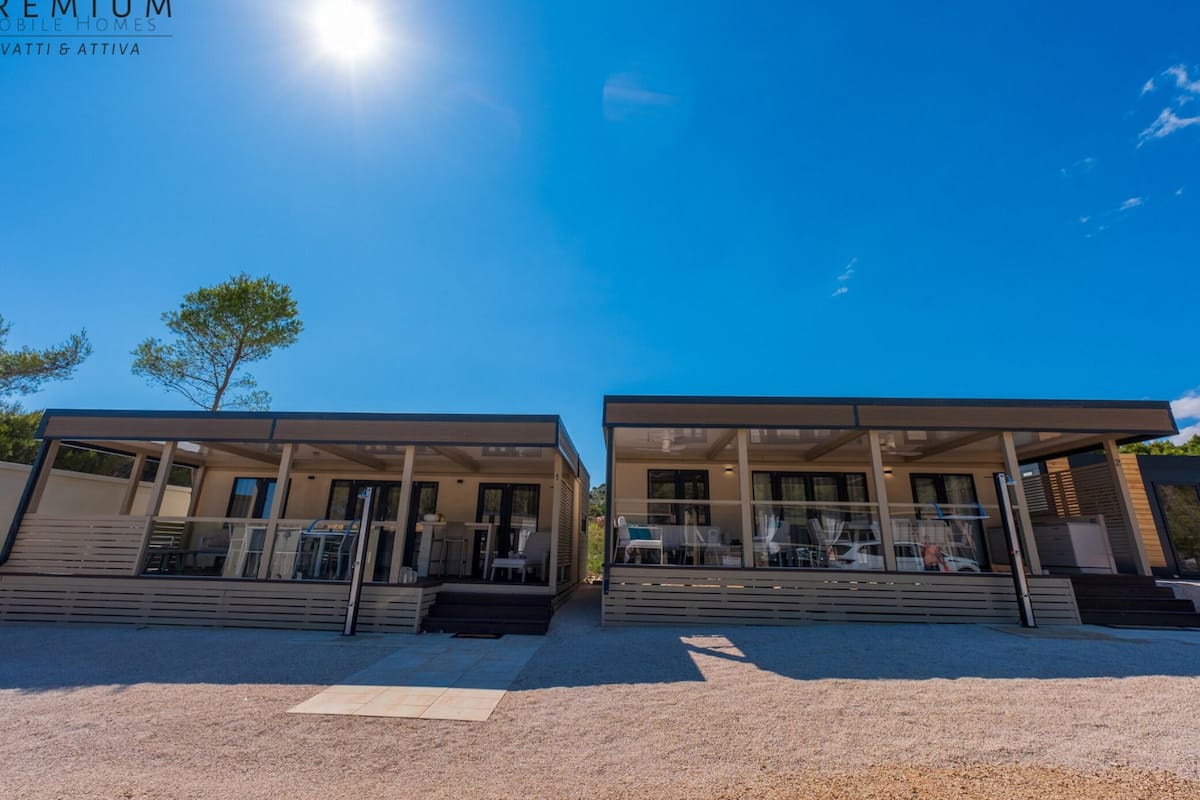 Eine moderne Villa mit überdachter Terrasse, einem Pool und blauem Himmel.