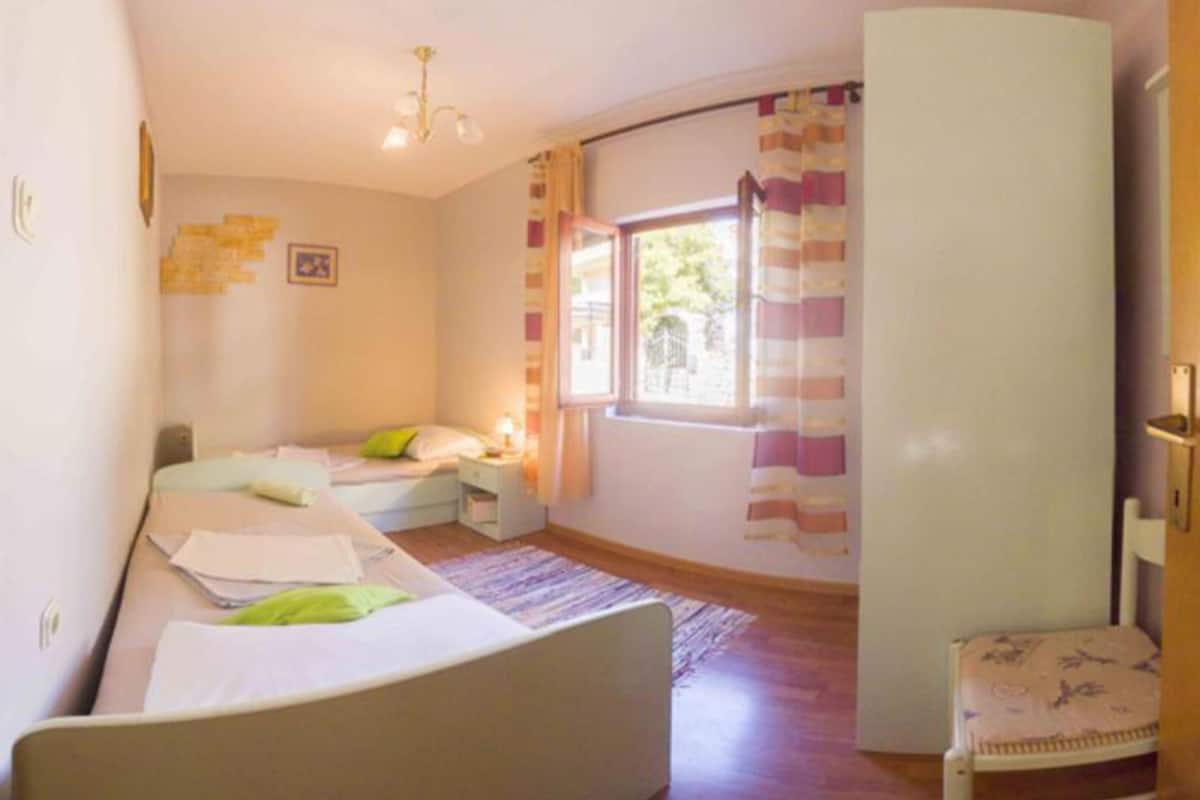 Un dormitorio con dos camas, una ventana con cortinas, un escritorio con papeles y una silla.
