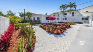 A two-story white house with a driveway and a landscaped garden. - Cozy Miami Studio | Free Parking | Gym | BBQ (Miami)