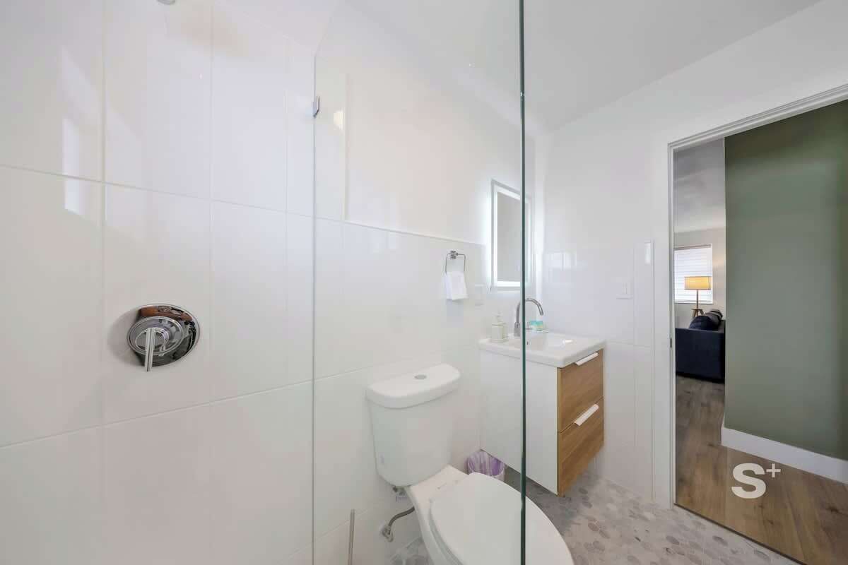 A modern bathroom with a glass shower enclosure, a toilet, and a sink.