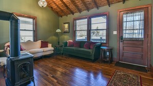 Una sala de estar acogedora con techo de madera, chimenea, sofá verde y puerta de madera.