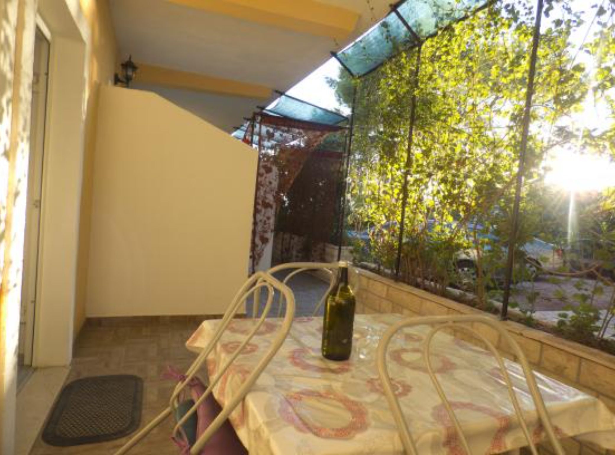 Un balcón con una mesa, una silla y una botella de vino.
