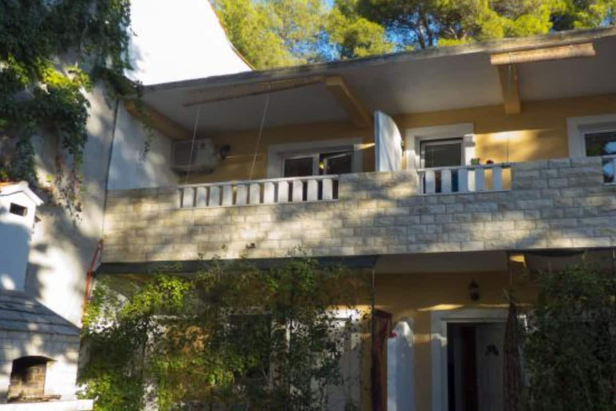 Un bâtiment à deux étages, doté d’une façade en pierre, d’un balcon à l’étage supérieur et d’une petite entrée avec une porte.