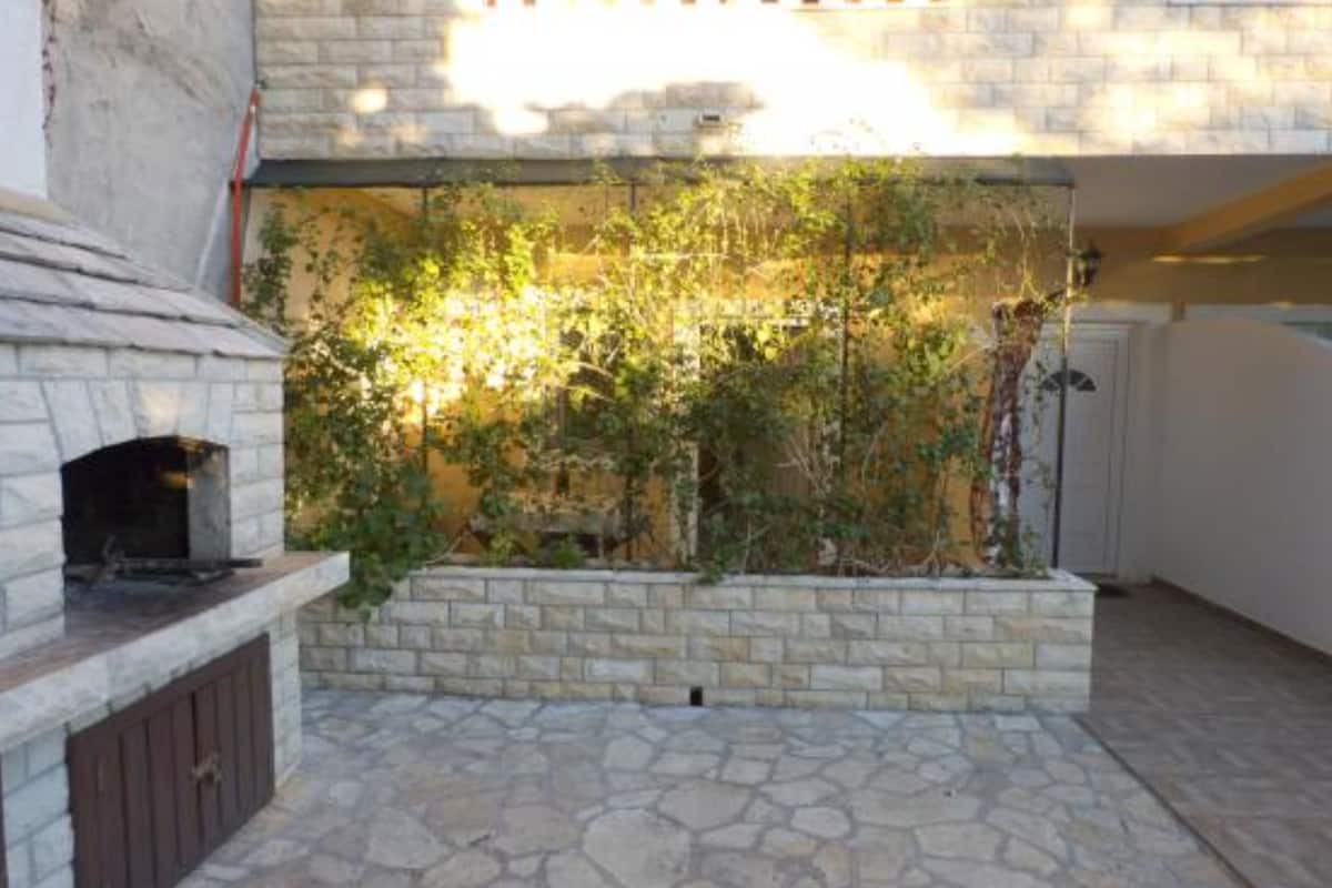 Une terrasse en pierre avec un foyer intégré et un mur recouvert de plantes grimpantes.