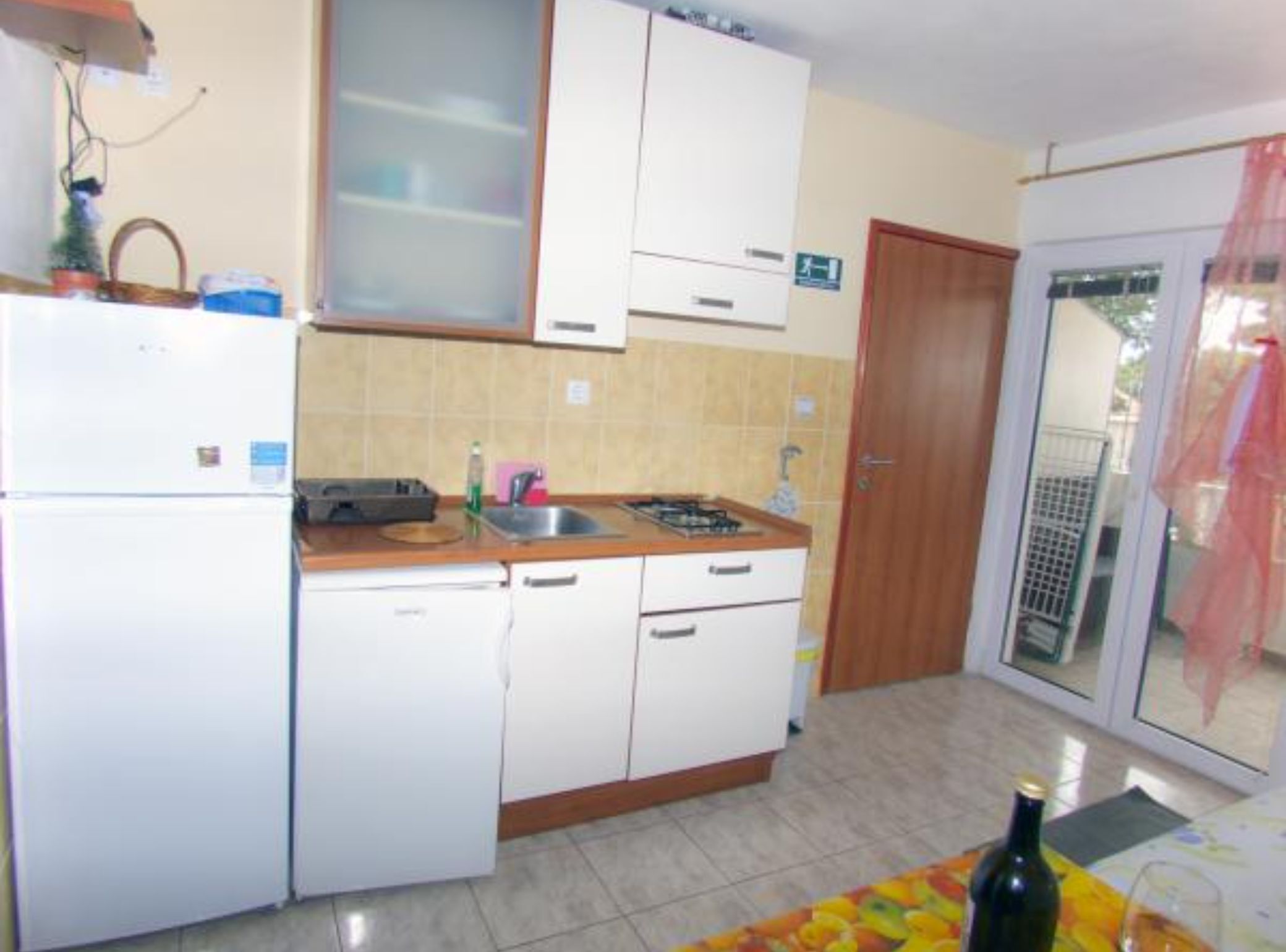 Een kleine keuken met witte kastjes, een spoelbak en een fornuis.