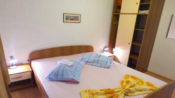 Quarto com cama, mesa de cabeceira, guarda-roupa e quadro na parede.