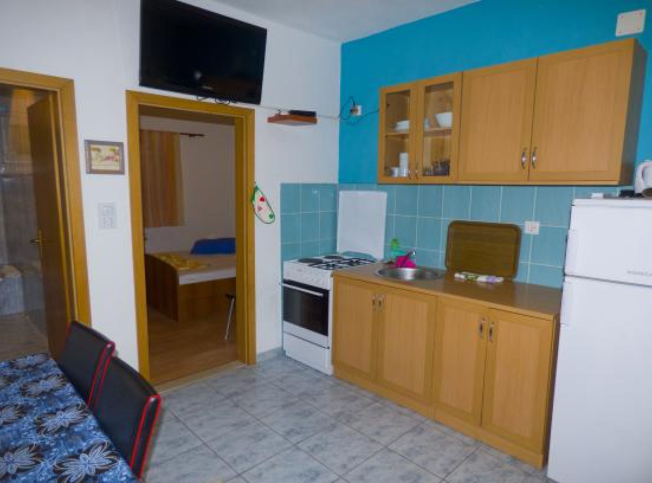 A compact kitchen with wooden cabinets, a stove, and a refrigerator.