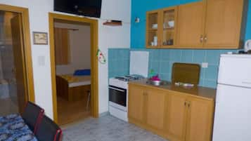 A compact kitchen with wooden cabinets, a stove, and a refrigerator.