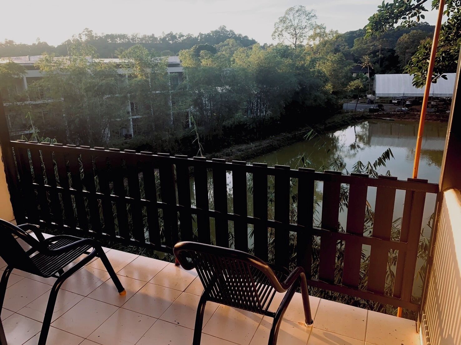 A balcony with two chairs and a view of a river and trees.