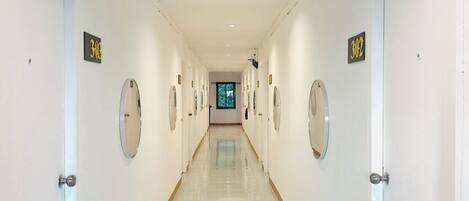 A long, well-lit hallway with doors on both sides, each marked with a number sign.