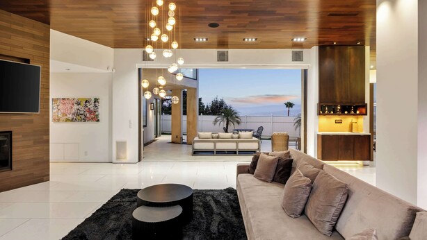 A modern living room with a sofa, a black rug, and a wooden ceiling.
