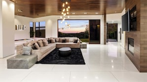 A modern living room with a sectional sofa, a round coffee table, and a large window with a view.