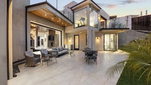 A modern house with a patio, outdoor furniture, and a large glass door.